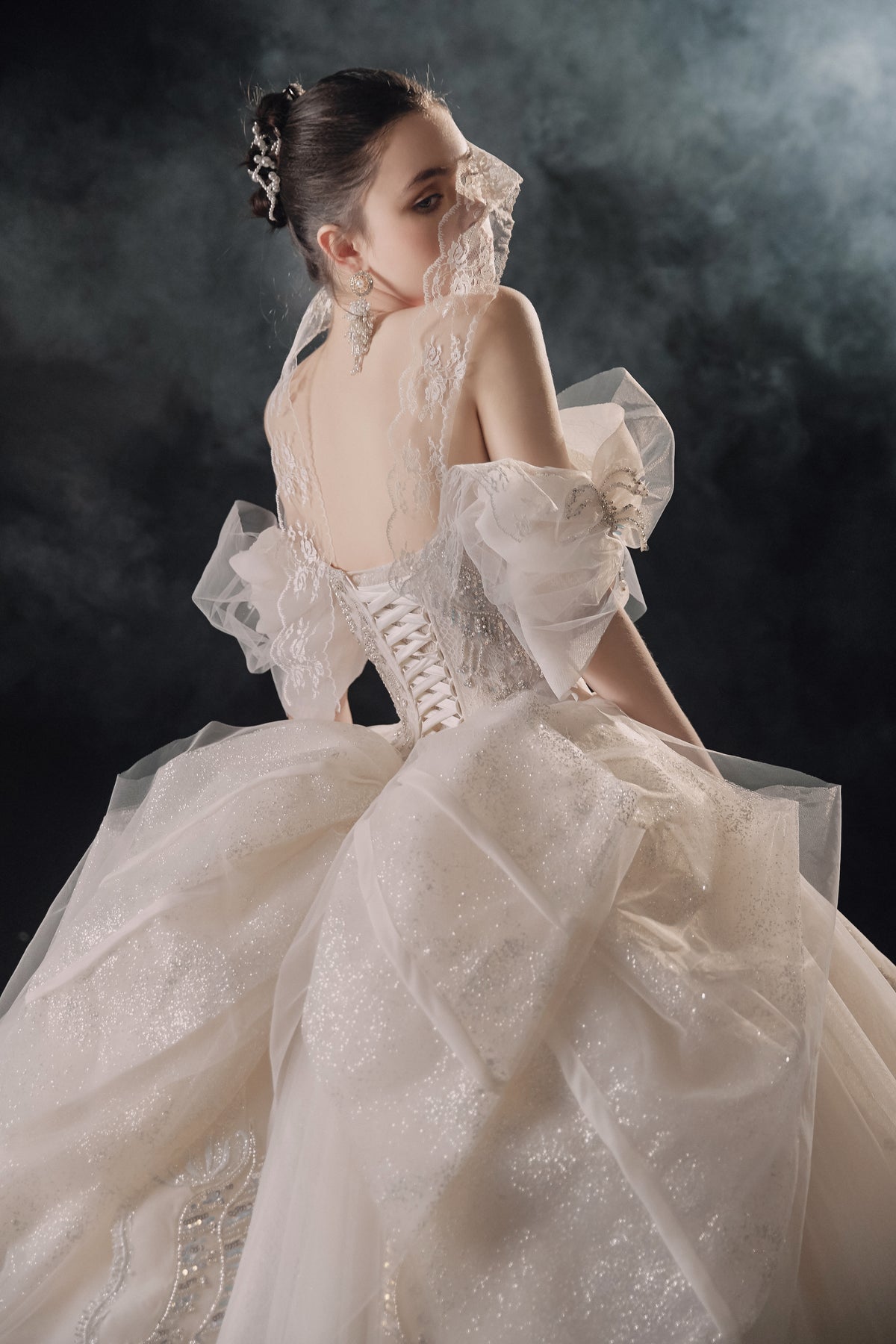 Vestido de Noiva Etéreo com Ombros Descobertos, Laço de Tule e Saia Rodada, com Cauda de Catedral e Aplicações de Renda com Cristais