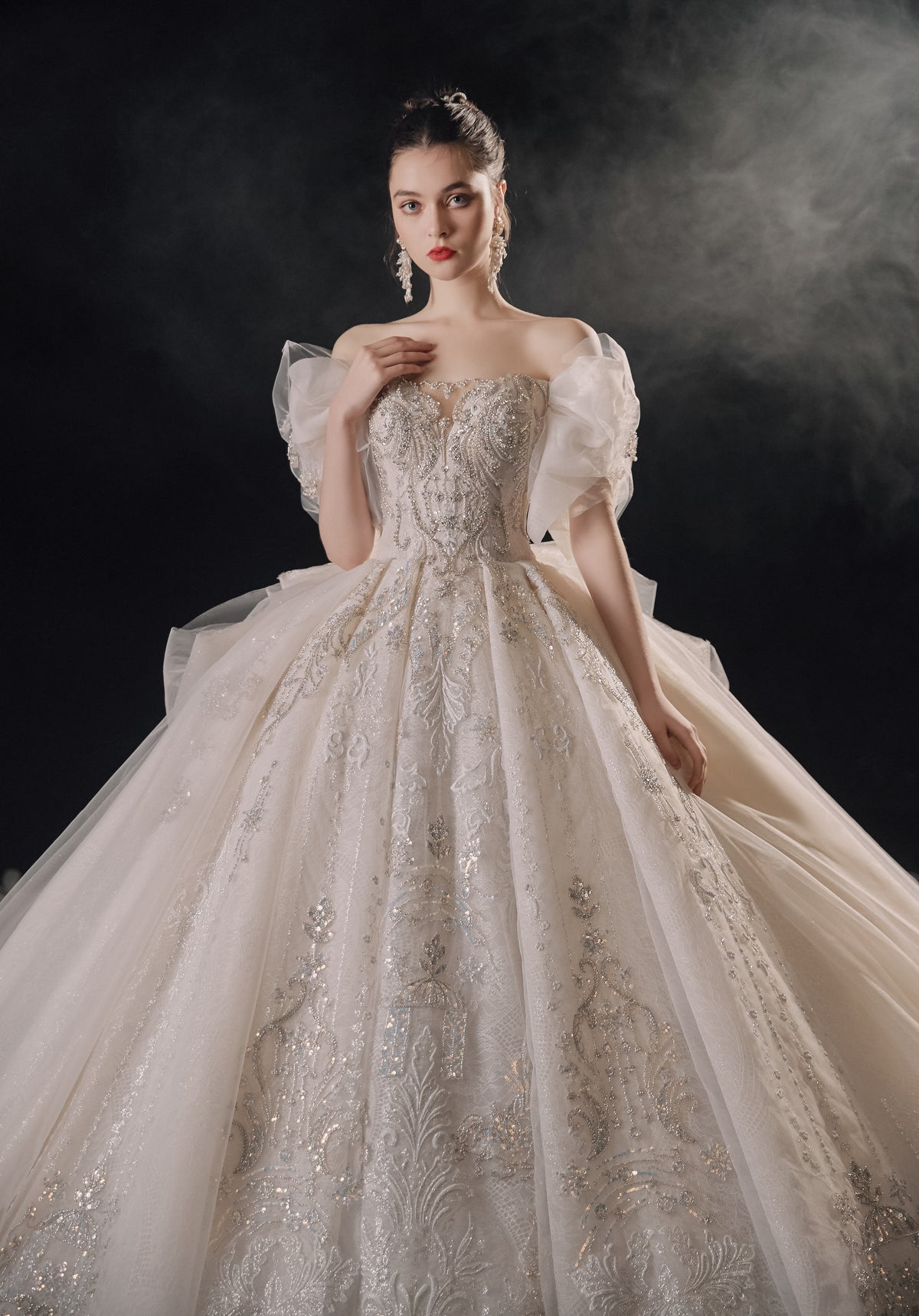 Vestido de Noiva Etéreo com Ombros Descobertos, Laço de Tule e Saia Rodada, com Cauda de Catedral e Aplicações de Renda com Cristais