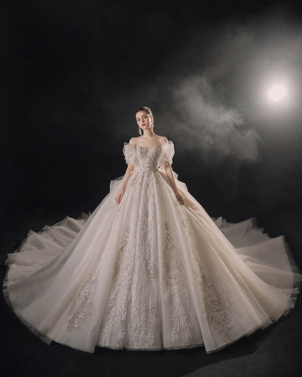 Vestido de Noiva Etéreo com Ombros Descobertos, Laço de Tule e Saia Rodada, com Cauda de Catedral e Aplicações de Renda com Cristais