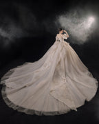 Vestido de Noiva Etéreo com Ombros Descobertos, Laço de Tule e Saia Rodada, com Cauda de Catedral e Aplicações de Renda com Cristais