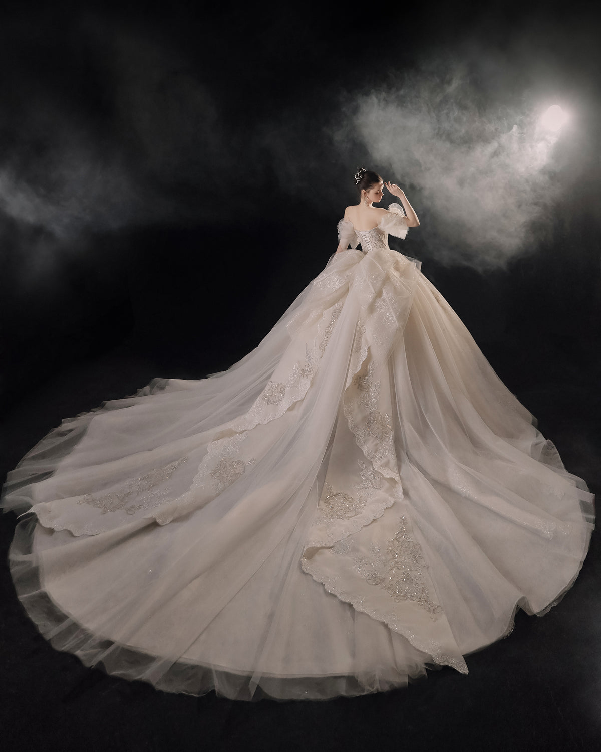 Vestido de Noiva Etéreo com Ombros Descobertos, Laço de Tule e Saia Rodada, com Cauda de Catedral e Aplicações de Renda com Cristais