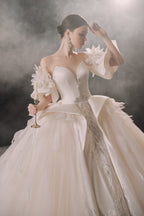 Abito da sposa etereo in raso con piume, scollatura a spalle scoperte, gonna ampia, strascico a cattedrale e dettagli in cristallo