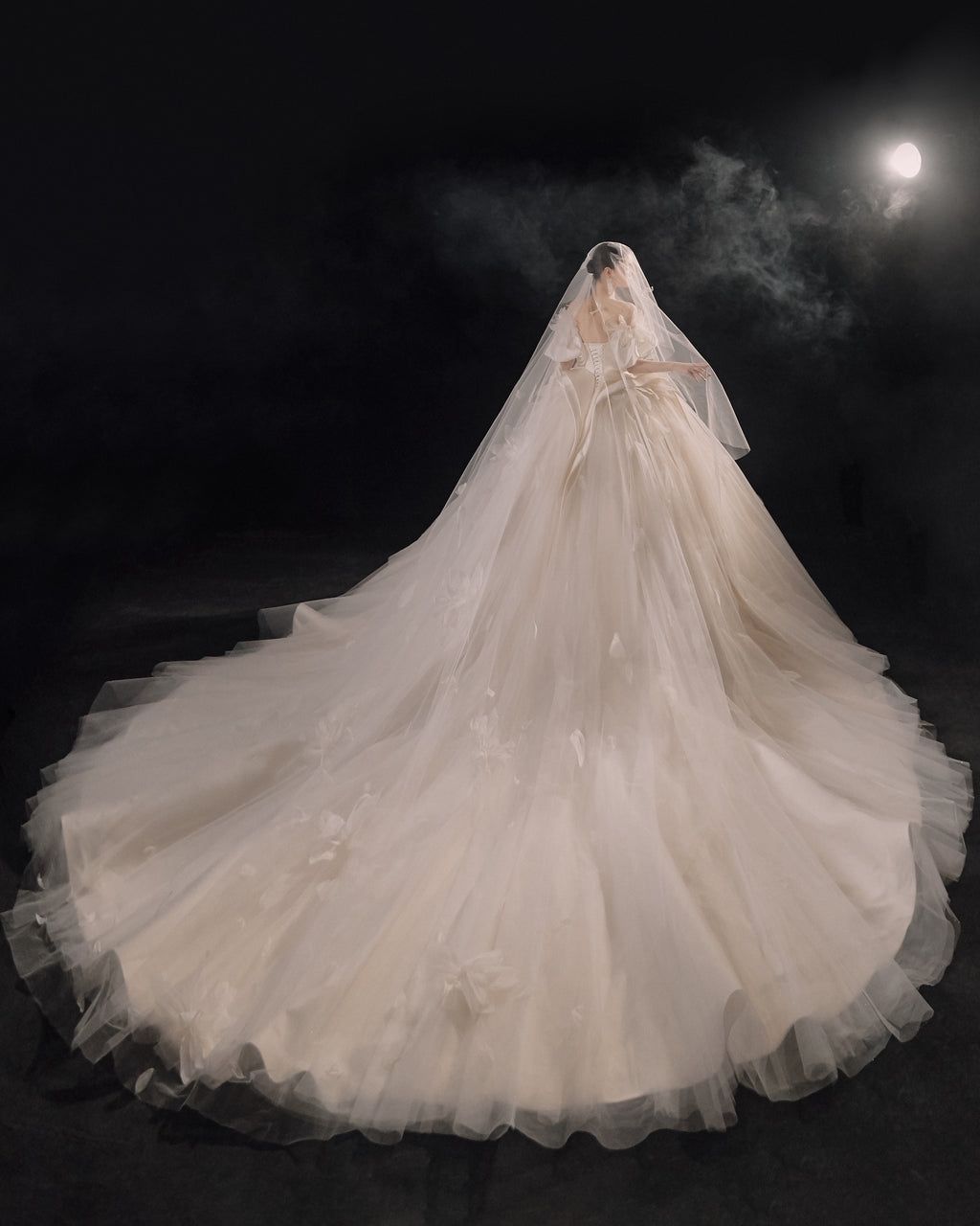 Abito da sposa etereo in raso con piume, scollatura a spalle scoperte, gonna ampia, strascico a cattedrale e dettagli in cristallo