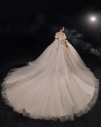 Abito da sposa etereo in raso con piume, scollatura a spalle scoperte, gonna ampia, strascico a cattedrale e dettagli in cristallo