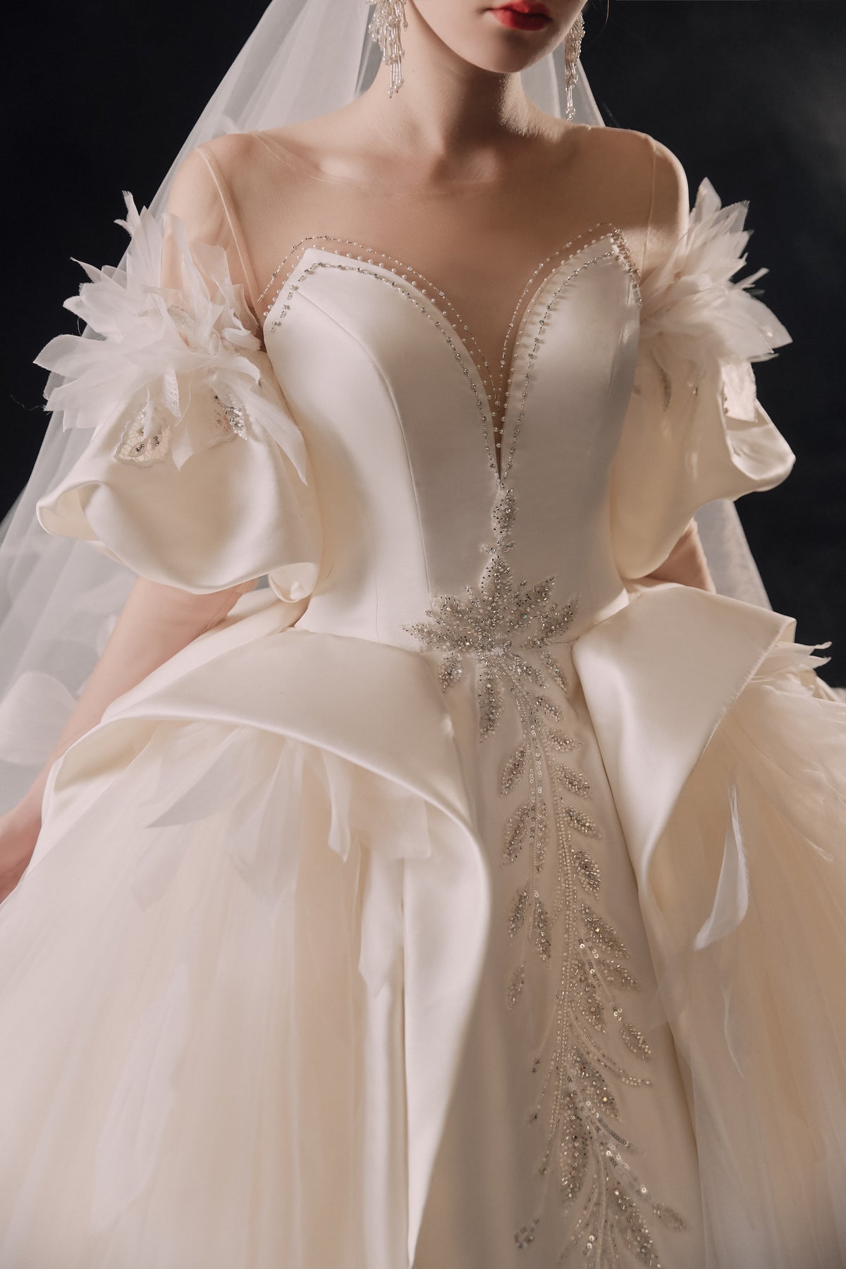 Abito da sposa etereo in raso con piume, scollatura a spalle scoperte, gonna ampia, strascico a cattedrale e dettagli in cristallo