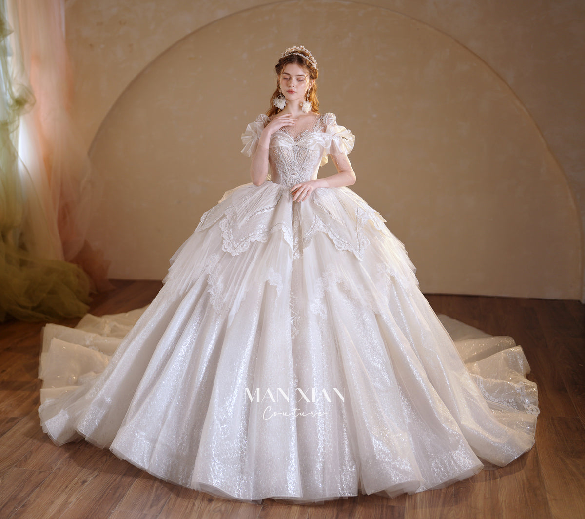 Abito da sposa etereo con scollo a spalle scoperte, gonna a sfera, strascico a cattedrale e applicazioni di pizzo