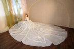 Abito da sposa etereo con scollo a spalle scoperte, gonna a sfera, strascico a cattedrale e applicazioni di pizzo