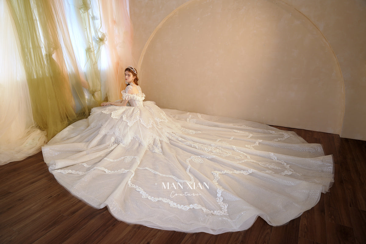 Abito da sposa etereo con scollo a spalle scoperte, gonna a sfera, strascico a cattedrale e applicazioni di pizzo
