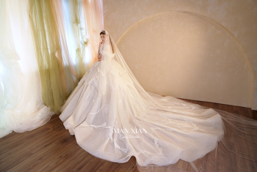 Abito da sposa etereo con scollo a spalle scoperte, gonna a sfera, strascico a cattedrale e applicazioni di pizzo