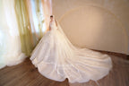 Abito da sposa etereo con scollo a spalle scoperte, gonna a sfera, strascico a cattedrale e applicazioni di pizzo