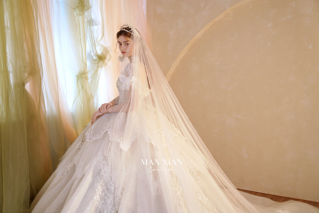Abito da sposa etereo con scollo a spalle scoperte, gonna a sfera, strascico a cattedrale e applicazioni di pizzo