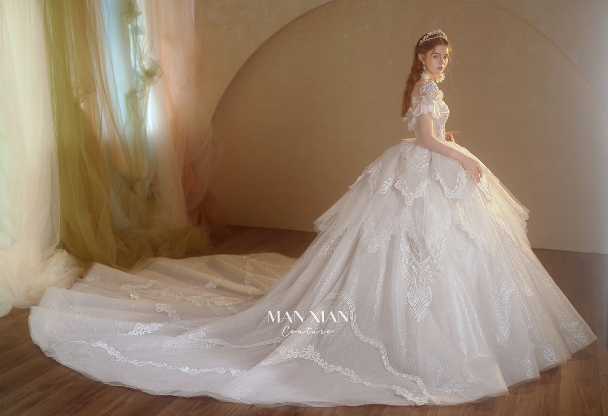 Abito da sposa etereo con scollo a spalle scoperte, gonna a sfera, strascico a cattedrale e applicazioni di pizzo