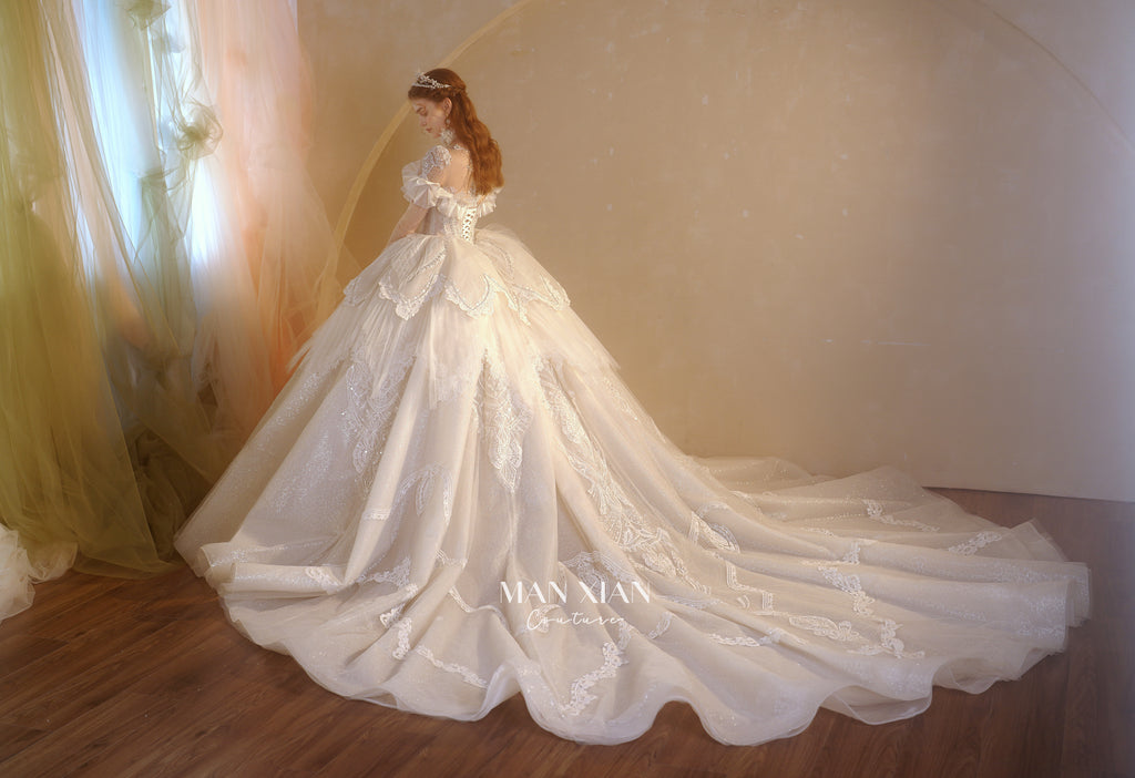 Abito da sposa etereo con scollo a spalle scoperte, gonna a sfera, strascico a cattedrale e applicazioni di pizzo