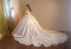Abito da sposa etereo con scollo a spalle scoperte, gonna a sfera, strascico a cattedrale e applicazioni di pizzo