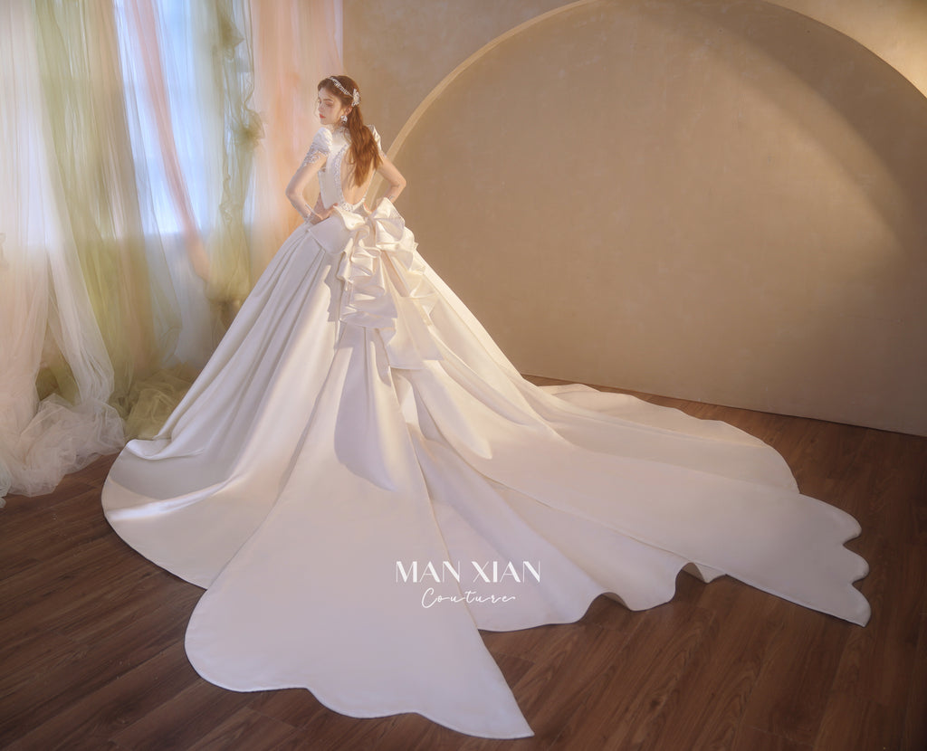 Abito da sposa di raso cristallino con scollo a V, gonna a palloncino, fiocco posteriore oversize e strascico a cattedrale