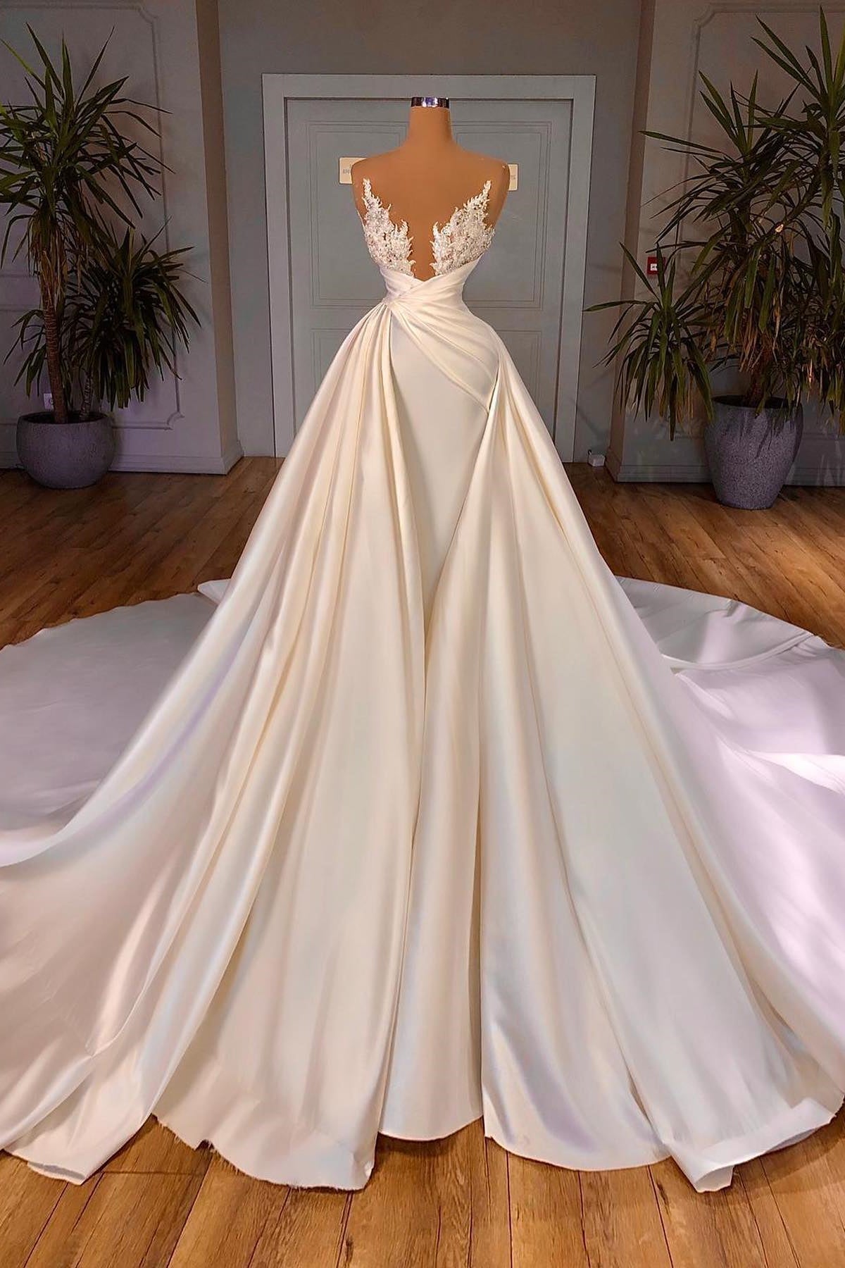 Elegante vestido de novia largo con escote en V, sin mangas y corte catedral.