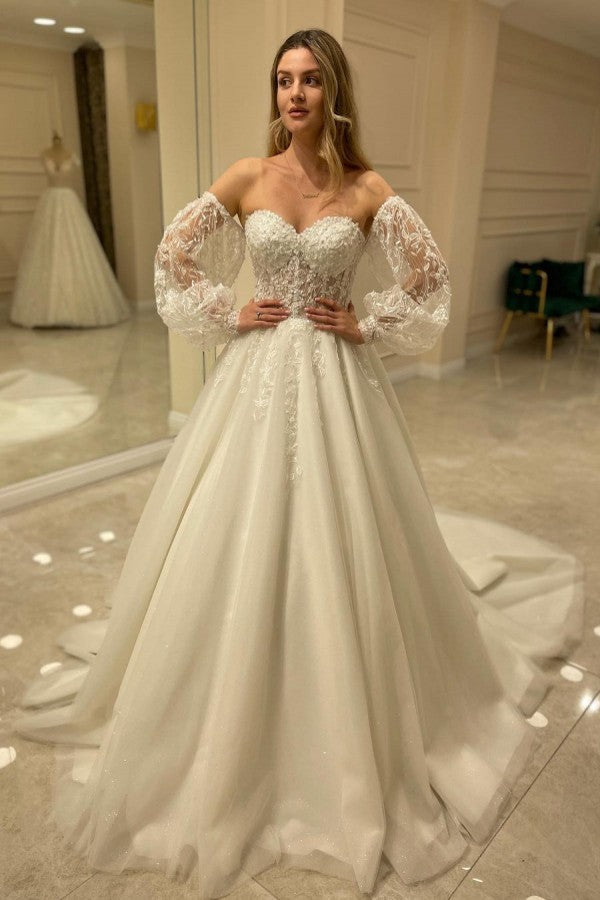 Abito da sposa elegante con maniche lunghe, linea a trapezio, scollo a cuore, schiena scoperta e applicazioni in pizzo