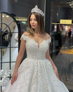Robe de mariée fabuleuse longue jusqu'au sol, décolleté cœur, épaules dénudées, coupe en A, ornée de paillettes avec volants