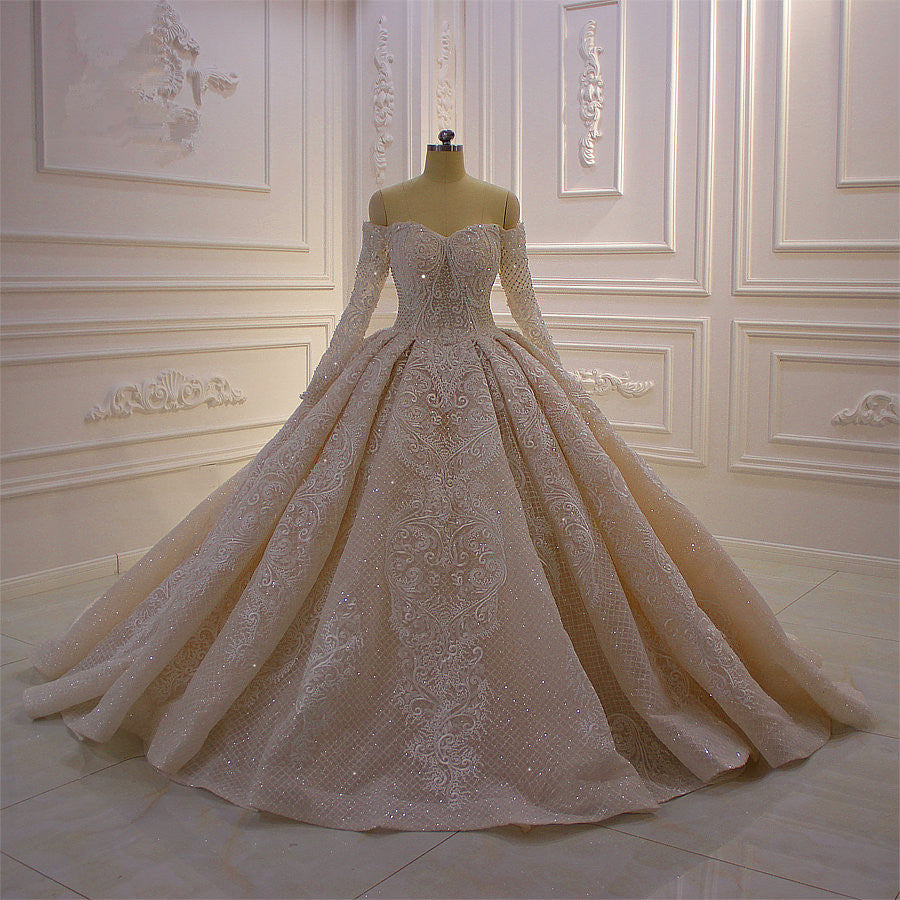 Splendido abito da sposa lungo con maniche lunghe, scollo a spalle scoperte, applicazioni e pizzo a balze