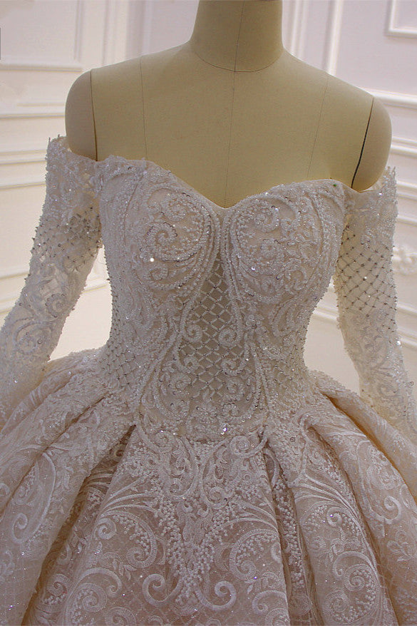 Splendido abito da sposa lungo con maniche lunghe, scollo a spalle scoperte, applicazioni e pizzo a balze