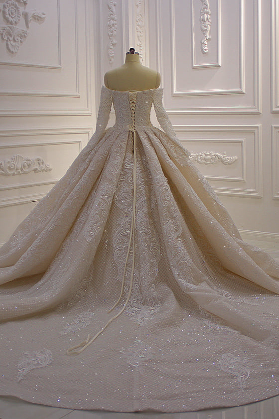 Splendido abito da sposa lungo con maniche lunghe, scollo a spalle scoperte, applicazioni e pizzo a balze