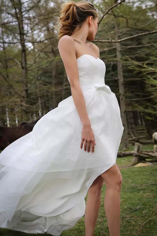 Vestido de novia de organza con apliques y escote corazón, sin mangas y corte alto bajo 