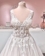 Vestido de noiva longo em linha A com decote em V, apliques de renda, costas descobertas, tule e folhos