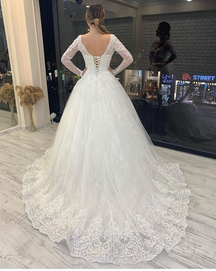Abito da sposa a maniche lunghe, linea a trapezio, scollo a V, applicazioni in pizzo, schiena scoperta in tulle