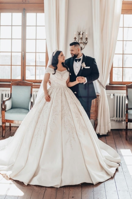 Lujoso vestido de novia blanco largo de satén con hombros descubiertos y encaje.