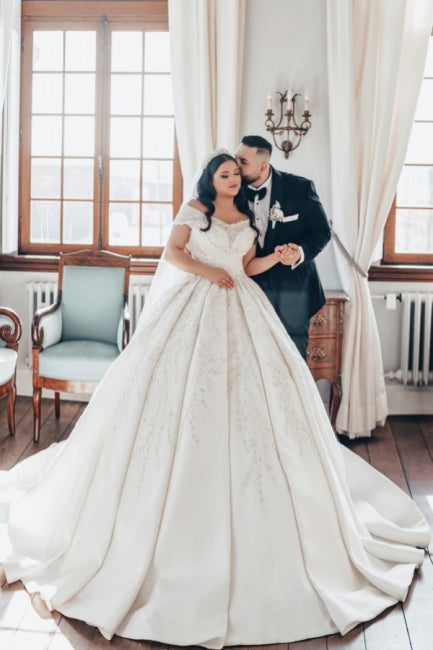 Lujoso vestido de novia blanco largo de satén con hombros descubiertos y encaje.